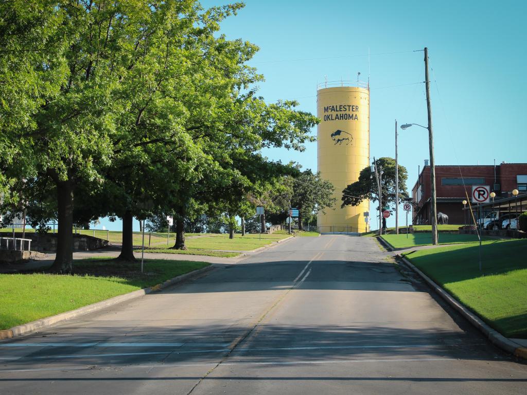 A view of an uphill water tower in McAlester, Oklahoma surrounded by trees