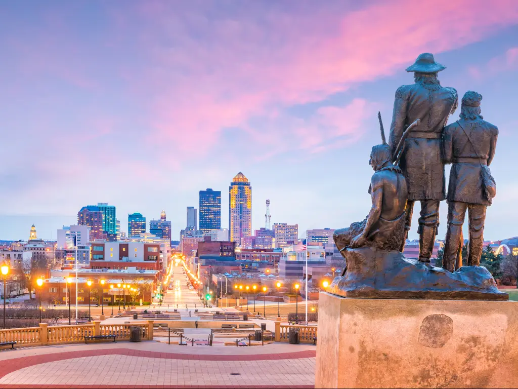 Pioneers of the Territory statue overlooking the skyline of the city of Des Moines, Iowa at sunset.