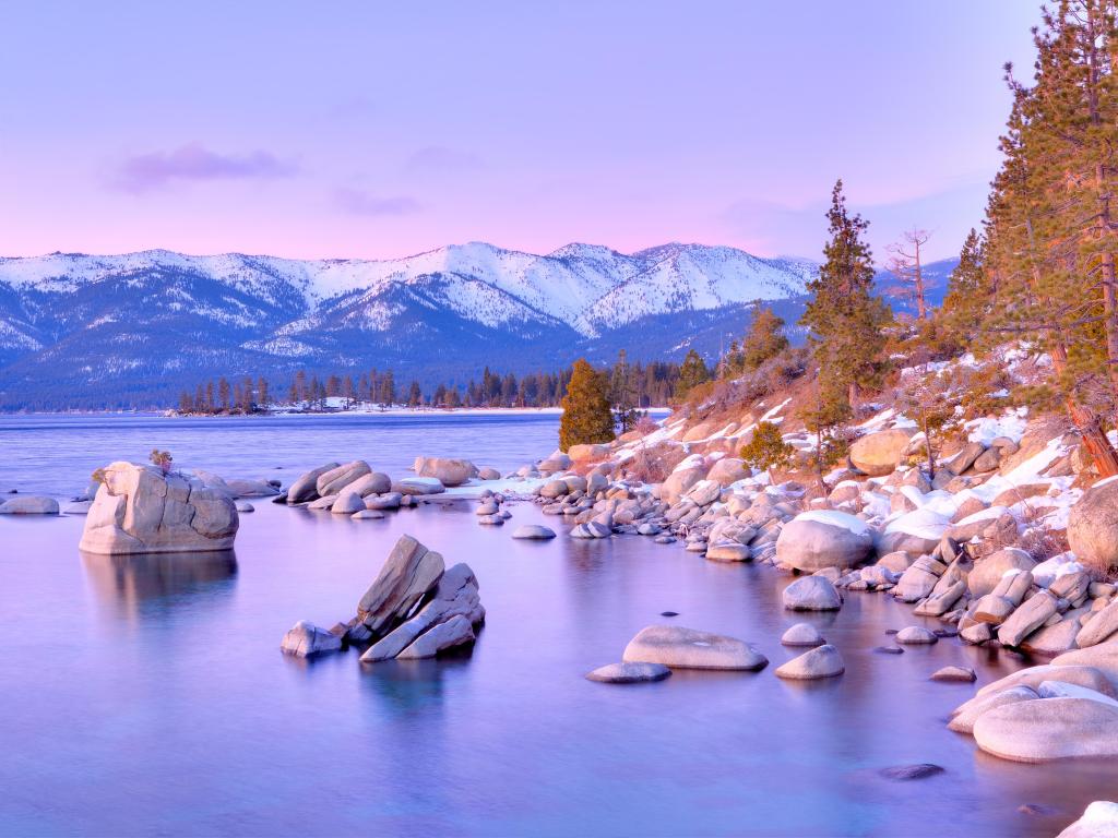 Lake Tahoe in winter during a beautiful sunset. There is snow on the stones in the lake. 