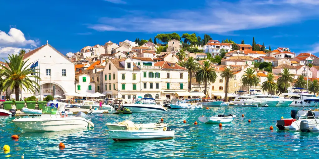 Boats in the turquoise water in the harbour of Hvar, Croatia, with white houses in the background