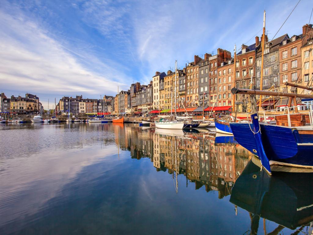 Honfleur harbor, Normandy, France on a sunny day with a view of the ships and buildings.