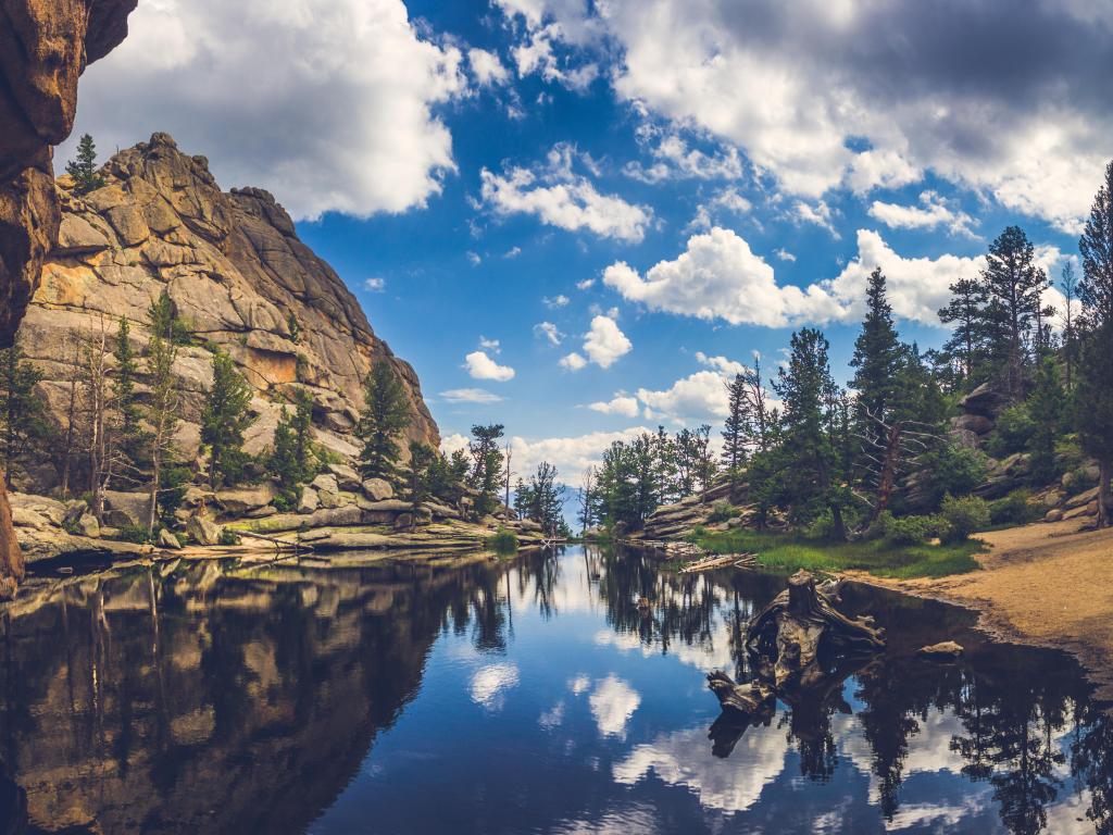 Perfectly still water on Gem Lake with reflection of blue sky, clouds, mountains, and trees, Estes Park, Colorado