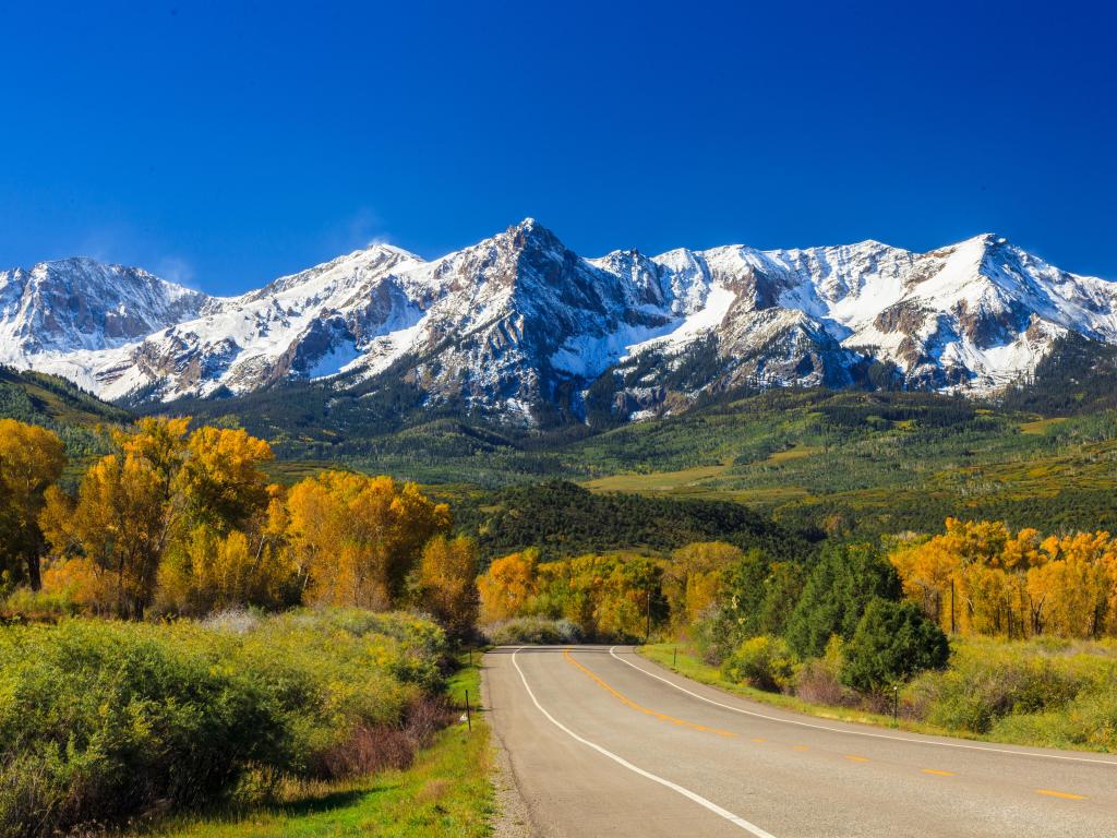 A country road running through the Rocky Mountains in Colorado during the fall.