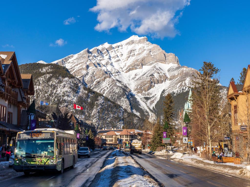 Downtown shopping street in Banff in the winter time on a sunny day, with traditional styled stores lining the street