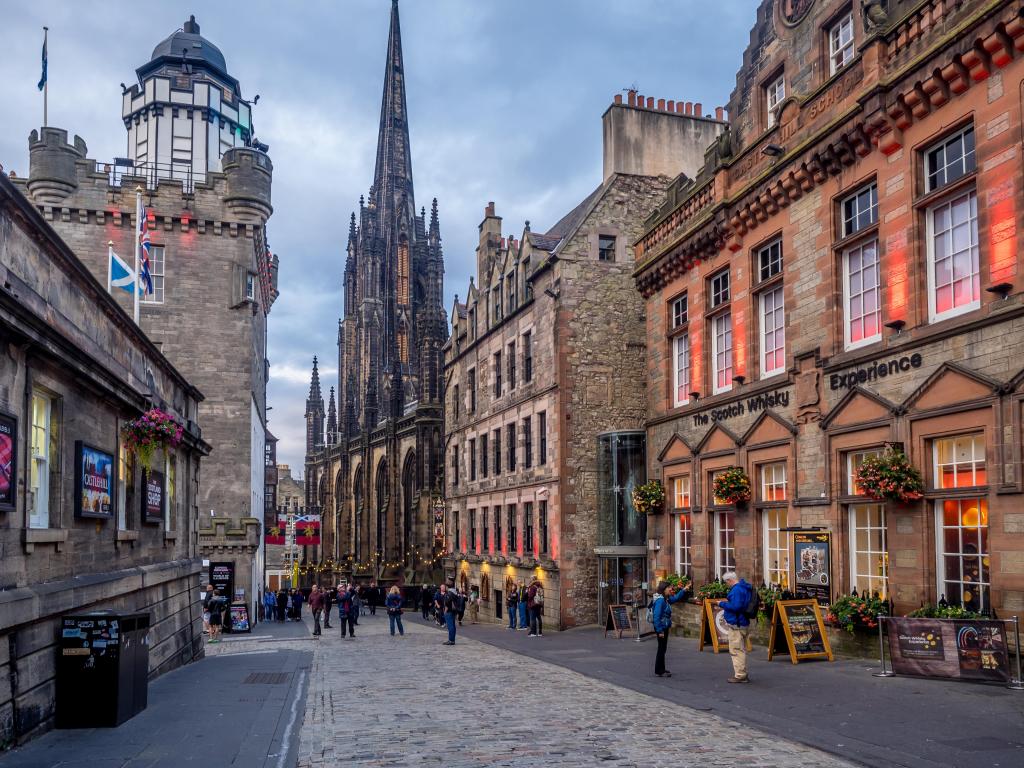  Looking down the slope of the Royal Mile in the Old Town in Edinburgh Scotland, dotted with shops and restaurants. Photo taken on a cloudy day.