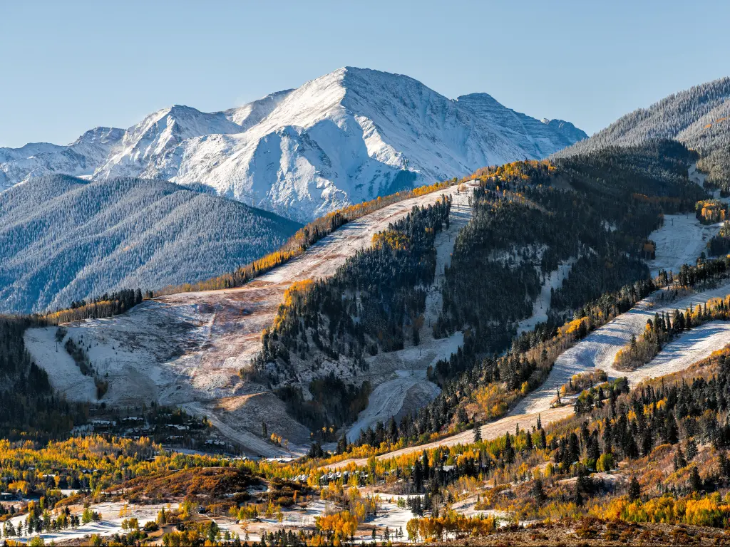 On a bright, sunny day, you can view the snow-capped peaks of the famous ski slopes at Buttermilk or Highlands in Aspen, Colorado. These are situated in the Rocky Mountains and beautifully contrast against the yellow foliage of autumn trees.