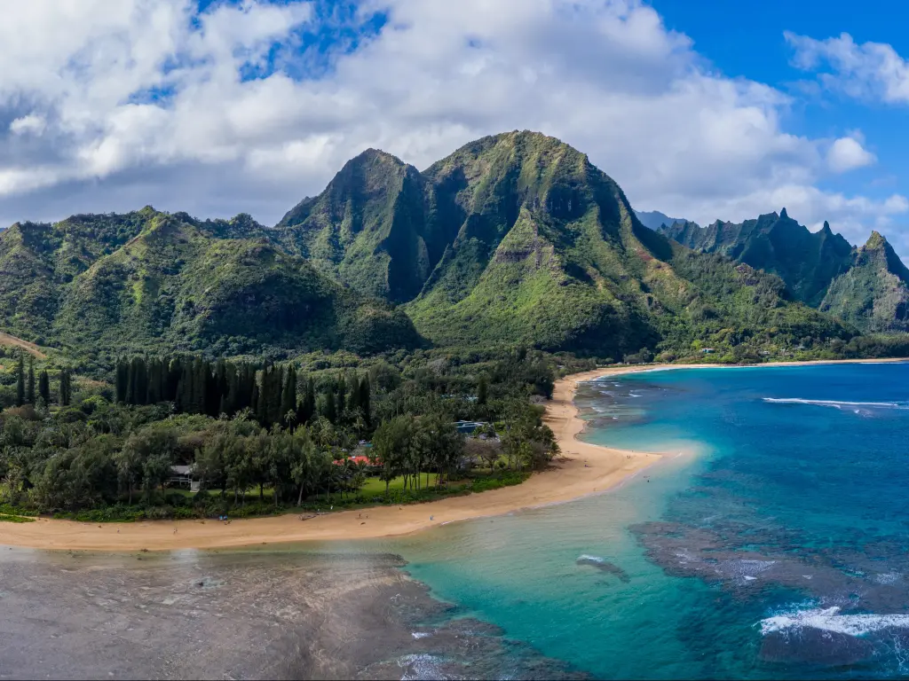 Aerial panoramic image off the coast over Tunnels beach on Hawaiian island of Kauai with Na Pali mountains behind.
