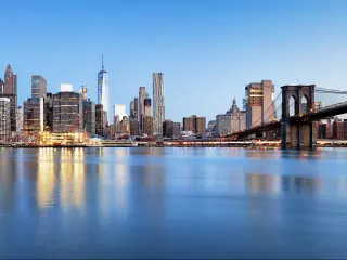 New York, USA with the Financial District and the Lower Manhattan at dawn viewed from the Brooklyn Bridge Park and reflecting in the water. 