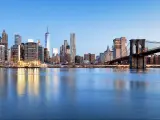 New York, USA with the Financial District and the Lower Manhattan at dawn viewed from the Brooklyn Bridge Park and reflecting in the water. 