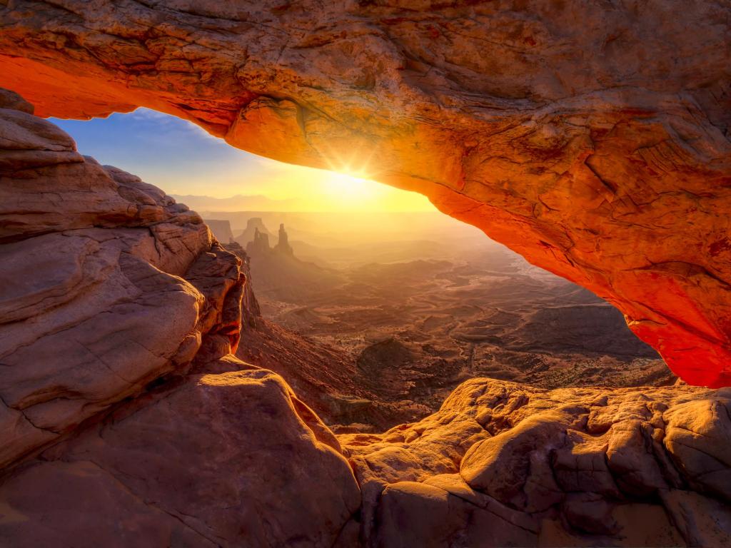 Iconic red arching rock formation at dawn near Moab, Utah, with sun shining through