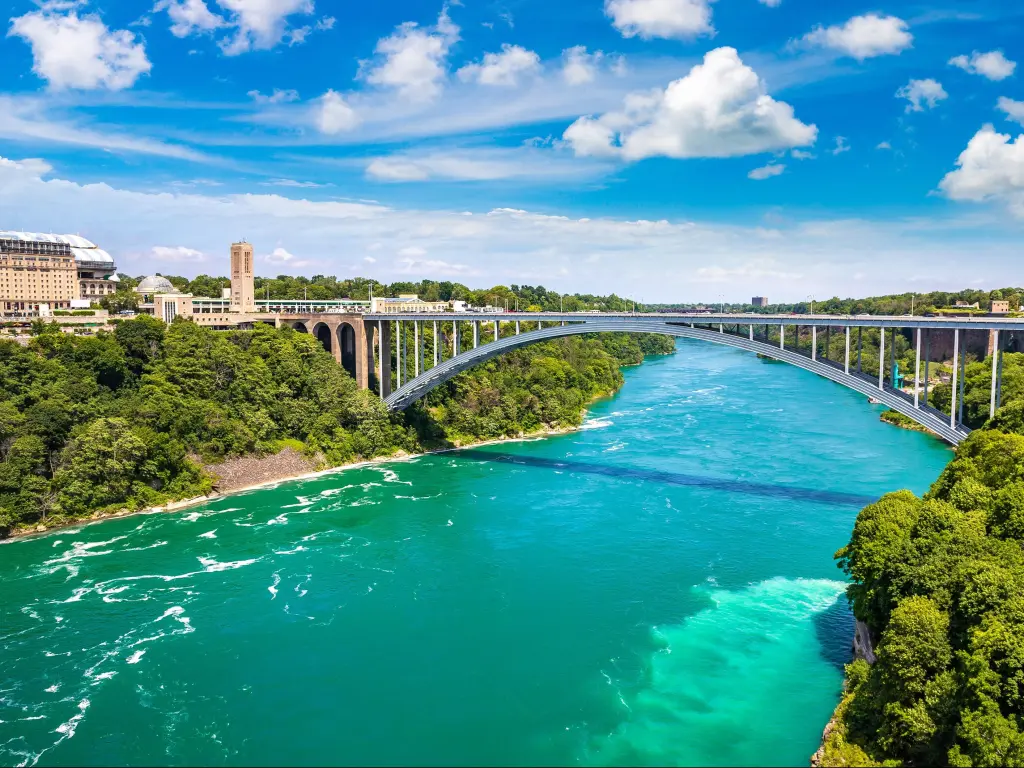 Rainbow International Bridge, USA/Canada with the Niagara River in the foreground and the bridge connecting the United States of America and Canada on a sunny day.