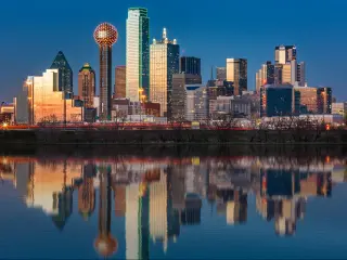 Dallas Texas Skyline with buildings reflected in the water and blue sky in the background