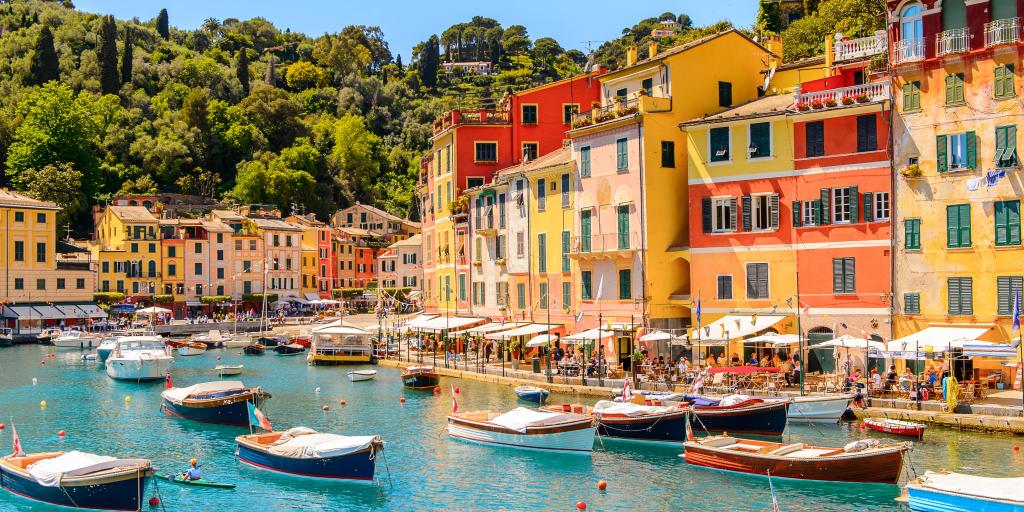 Boats in the turquoise blue water of the harbour in Portofino, Italy, with colourful townhouses in the background