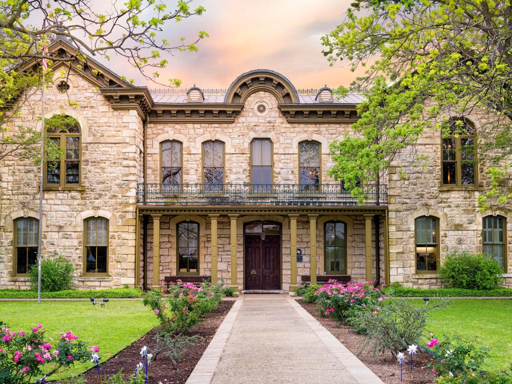 Public library in Fredericksburg, Texas with limestone veneer, sitting in a beautiful garden and flower borders