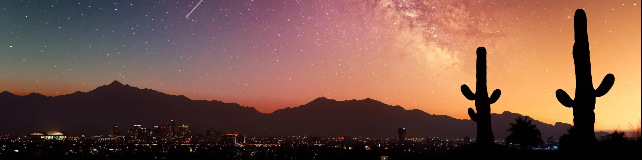 A starry sky with the Milky Way visible over the city of Phoenix, Arizona, with cacti in the foreground 