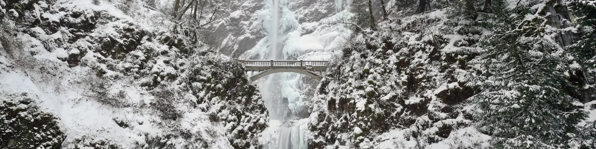Frozen waterfall with a beautiful bridge on a winter day with snow on the ground
