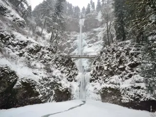 Frozen waterfall with a beautiful bridge on a winter day with snow on the ground