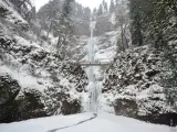 Frozen waterfall with a beautiful bridge on a winter day with snow on the ground