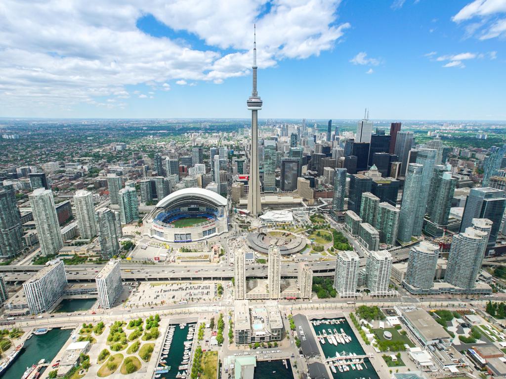 Aerial photo of the streets of the city with the CN Tower in the middle, blue skies