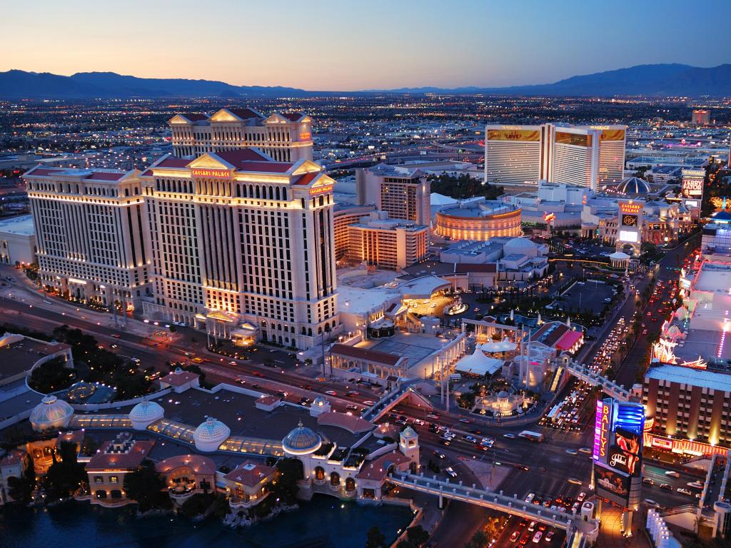 Las Vegas, Nevada, USA taken as an aerial view of the Las Vegas strip at night with mountains in the distance.