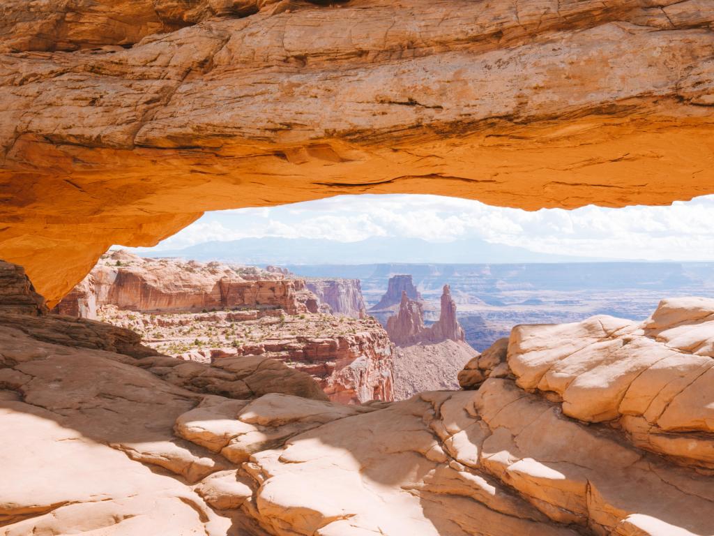 Classic view of famous Mesa Arch, symbol of the American Southwest, illuminated in scenic golden morning light at sunrise on a beautiful day in summer, Canyonlands National Park, Utah, USA