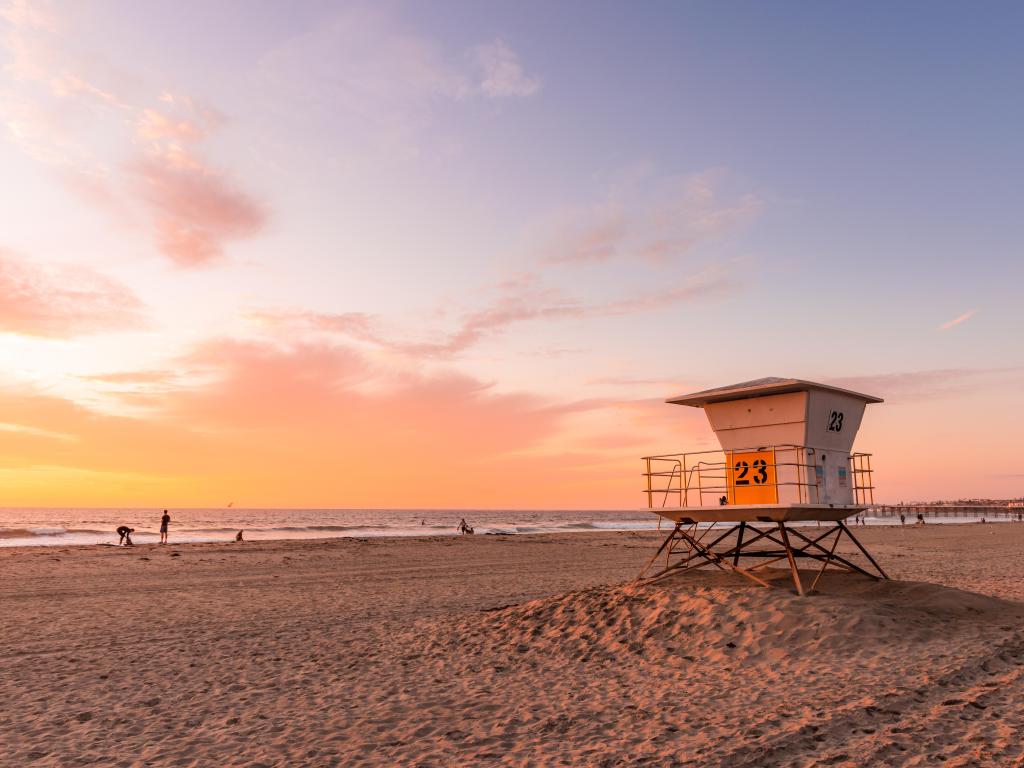 Malibu, California, USA with a view of a lifeguard tower on the beach at sunset.