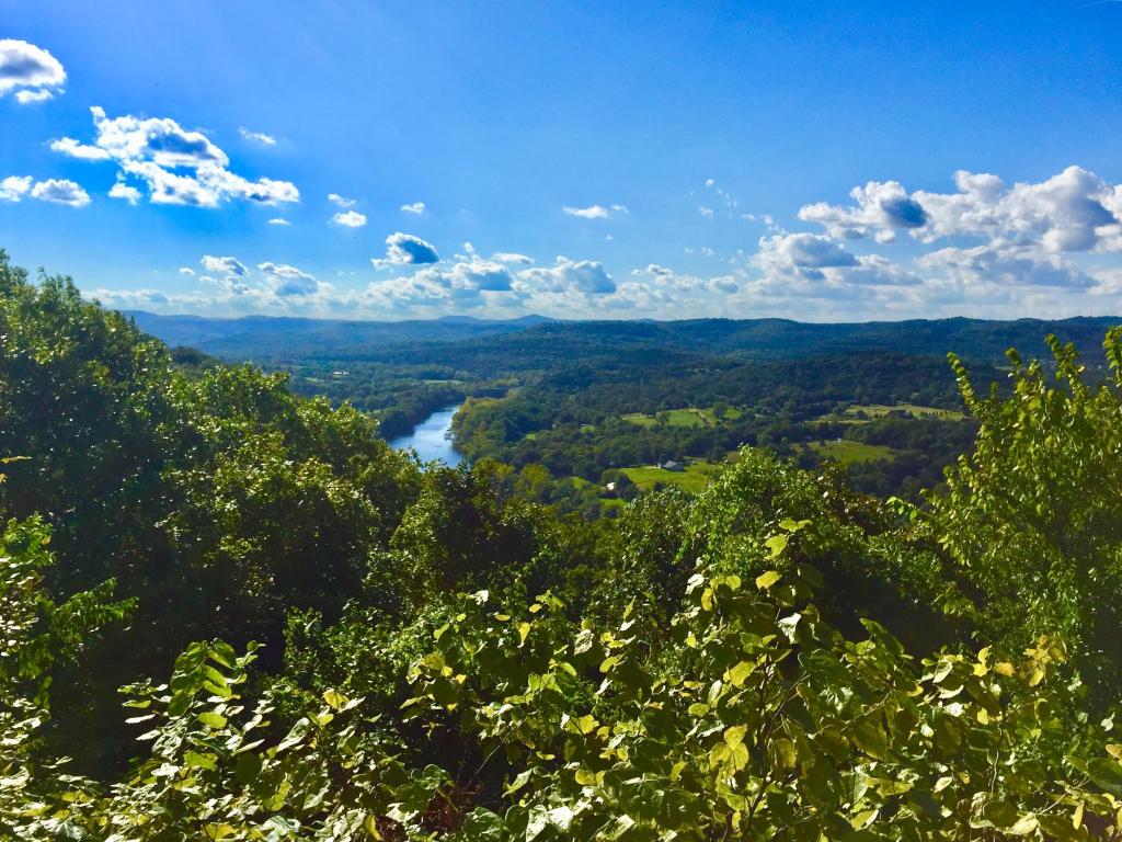 Eureka springs, Arkansas, USA with trees and valleys in the distance and a river against a blue sky.