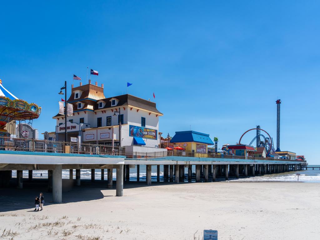 Galveston Island Historic Pleasure Pier is a pleasure pier that has many rides over water. Photo taken on a sunny day, depicting this pier on the sand and water.