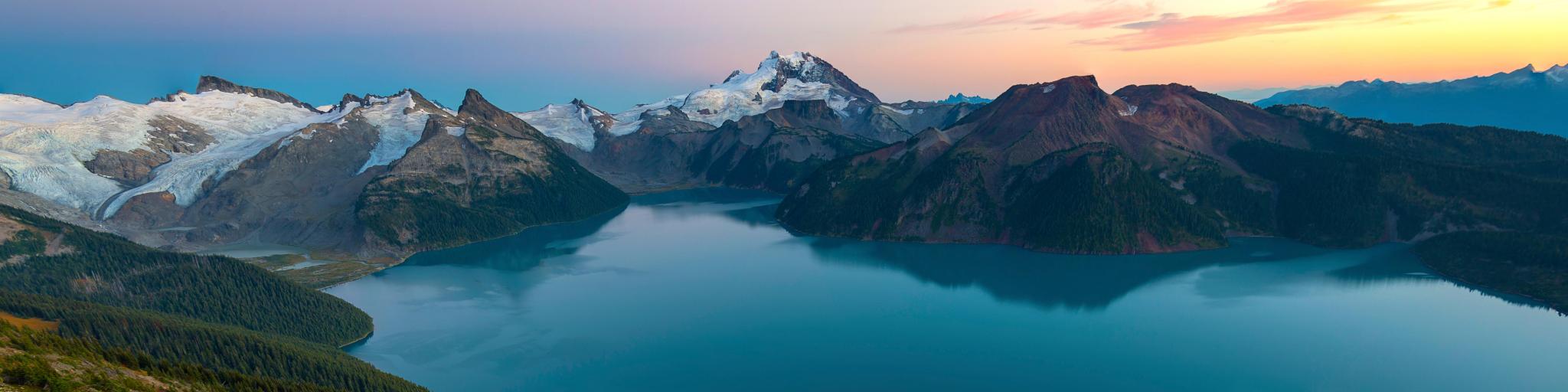 Garibaldi Provincial Park, Canada taken at sunset with a rocky landscape in the foreground, a lake and mountains in the distance. 