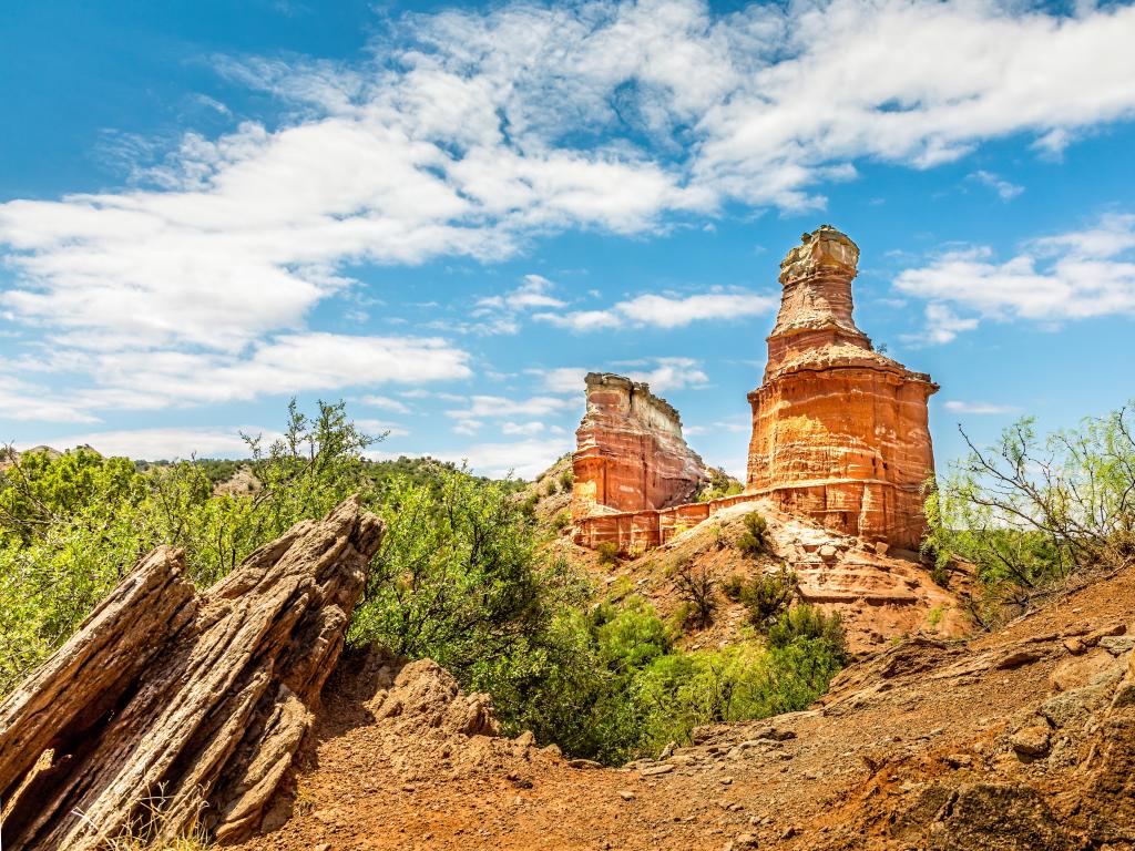 Palo Duro Canyon State Park, Texas, USA with the famous Lighthouse Rock and shrubs in the foreground, taken on a sunny day with wispy clouds. 