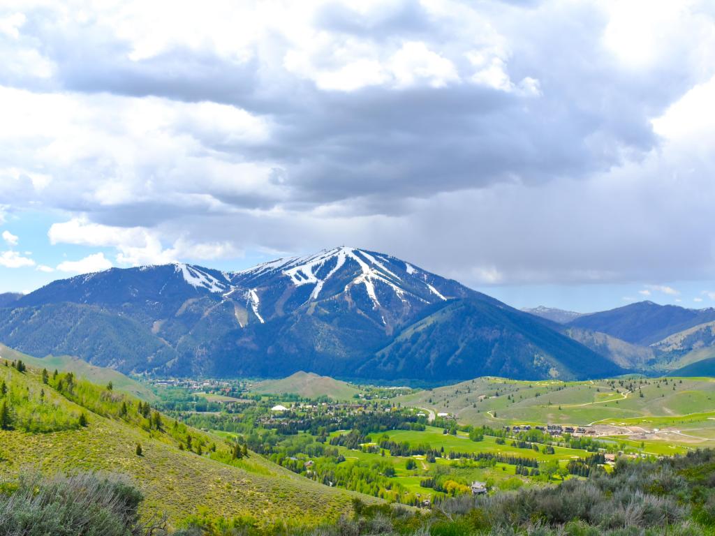 Ketchum Sun Valley, Idaho, USA looking down on the green valleys and snow-capped mountain in the distance on a cloudy but sunny day.