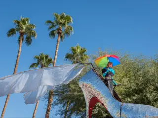 Giant silver sparkly stiletto and person holding rainbow flag