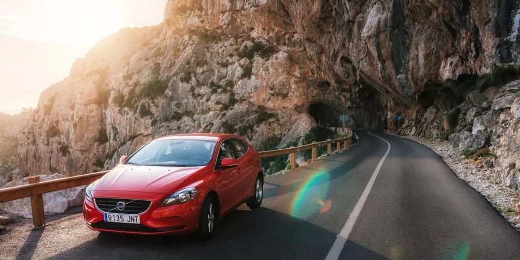 A red car driving on the right in the mountains in Spain 