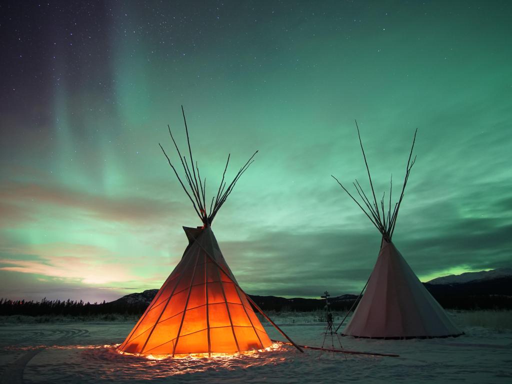 Tipis in Whitehorse, Yukon, Canada, glowing from within under a night sky with northern lights