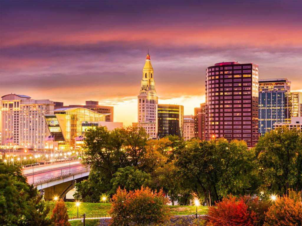 Hartford, Connecticut, USA with the downtown skyline taken at fall after sunset, beautiful red and orange colored trees in the foreground.