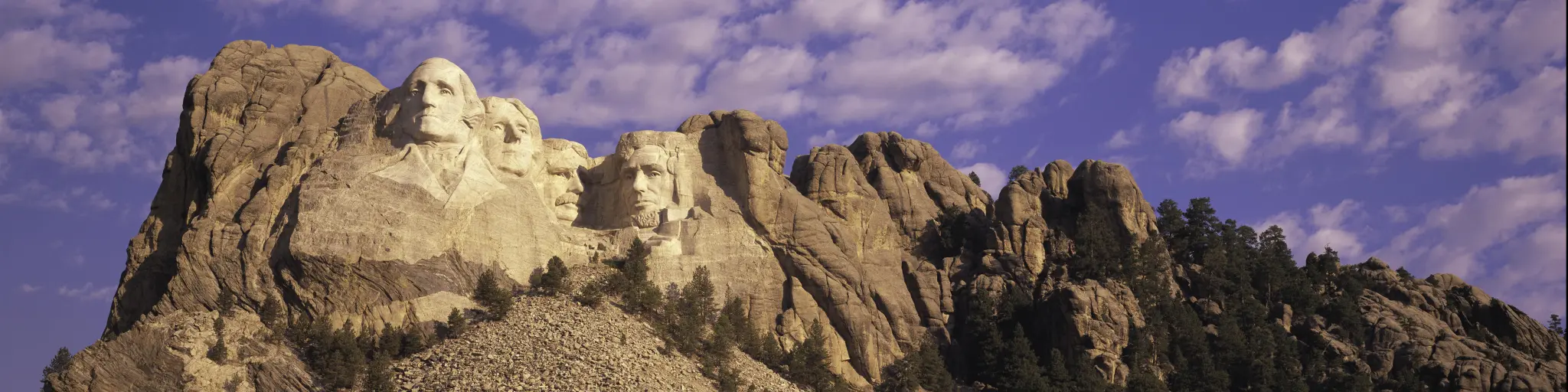 Mount Rushmore, South Dakota, with blue sky and puffy clouds behind