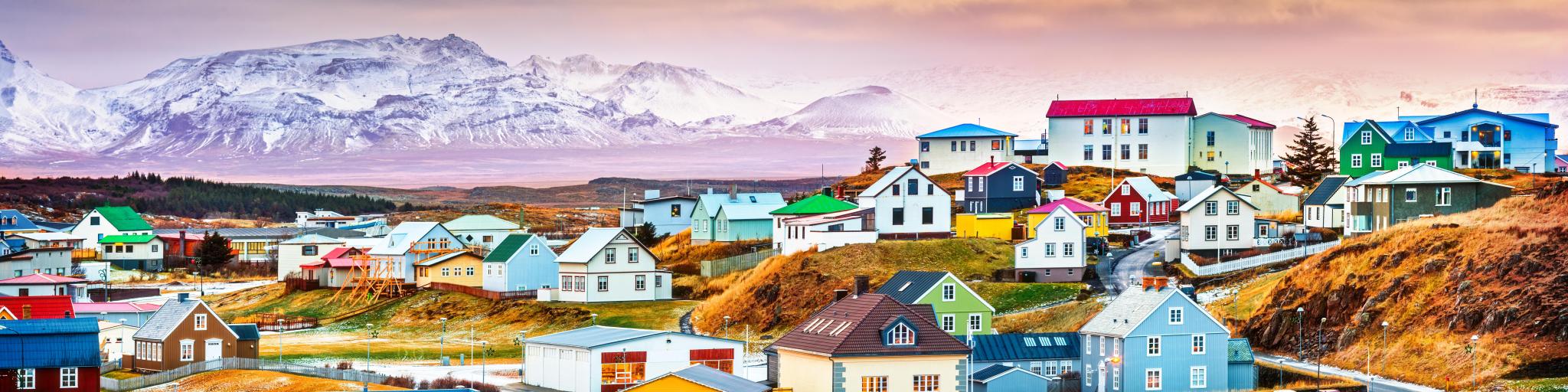  Colorful Icelandic houses with the backdrop of a majestic, snow-covered mountain, pink misty hue surrounding it