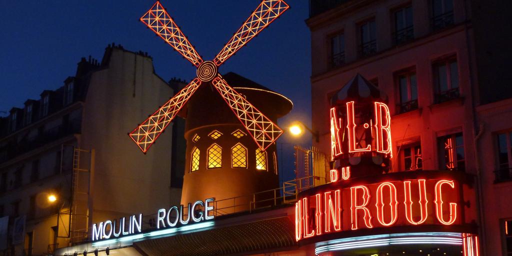 The neon lights of the Moulin Rouge lit up in the evening in Paris