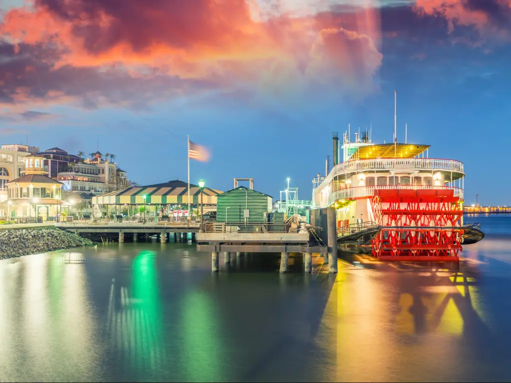 New Orleans, Louisiana, USA with a docked steamboat in New Orleans at early evening with a stunning sky and the pier lit up.