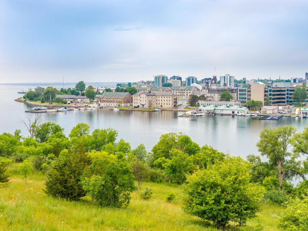 Kingston, Ontario, Canada taken with a view of the city from Fort Henry Hill, surrounded by green grass in the foreground and Lake Ontario.