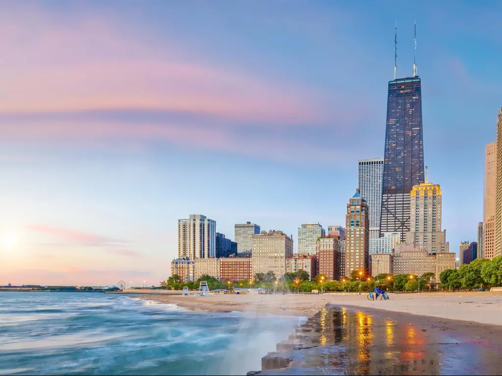 Chicago, Illinois, USA with the downtown city skyline the background at sunset and the shore of Lake Michigan in the foreground.