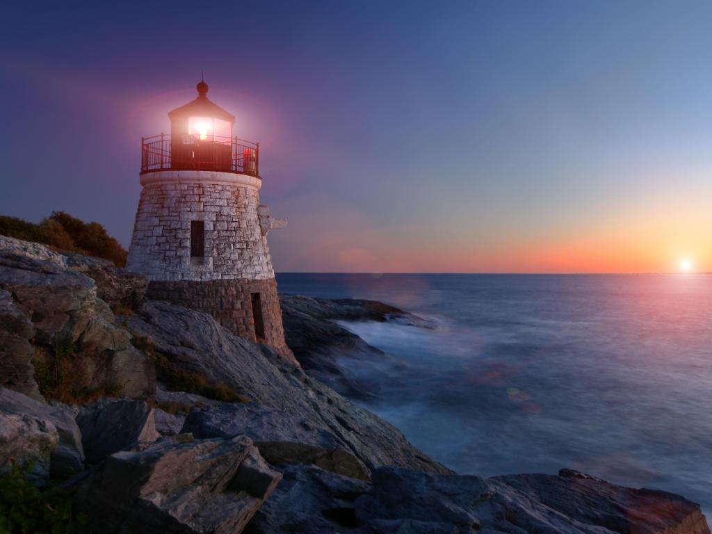 Newport, Rhode Island, USA taken at Castle Hill Lighthouse at sunset surrounded by the sea and rocks. 