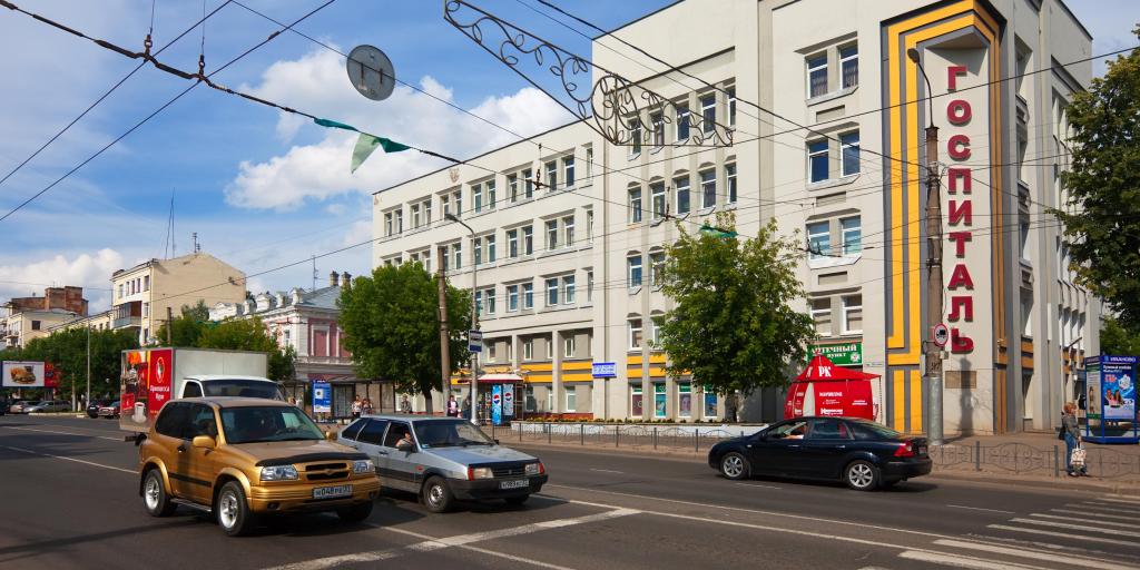 A street in Ivanovo, Russia, with cars going past a big rectangular grey building 