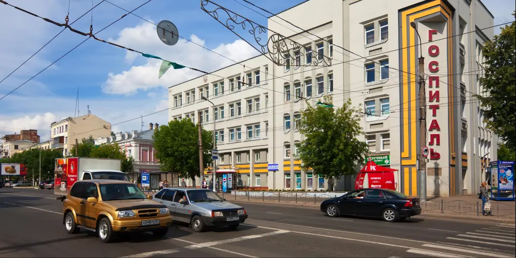A street in Ivanovo, Russia, with cars going past a big rectangular grey building 