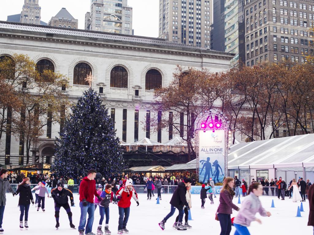 People ice skating on the seasonal rink with a Christmas Tree in the background