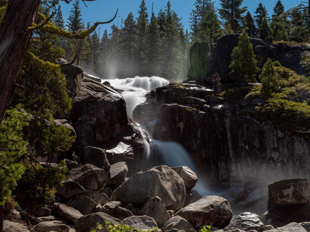 Waterfall at the Eldorado National Forest, California, viewed from a distance, featuring sierra vegetation of coniferous trees and rocks