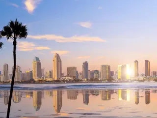 San Diego, California, USA  with the city downtown in the distance and the water reflecting the skyscrapers in the foreground, palm trees and taken at sunset. 