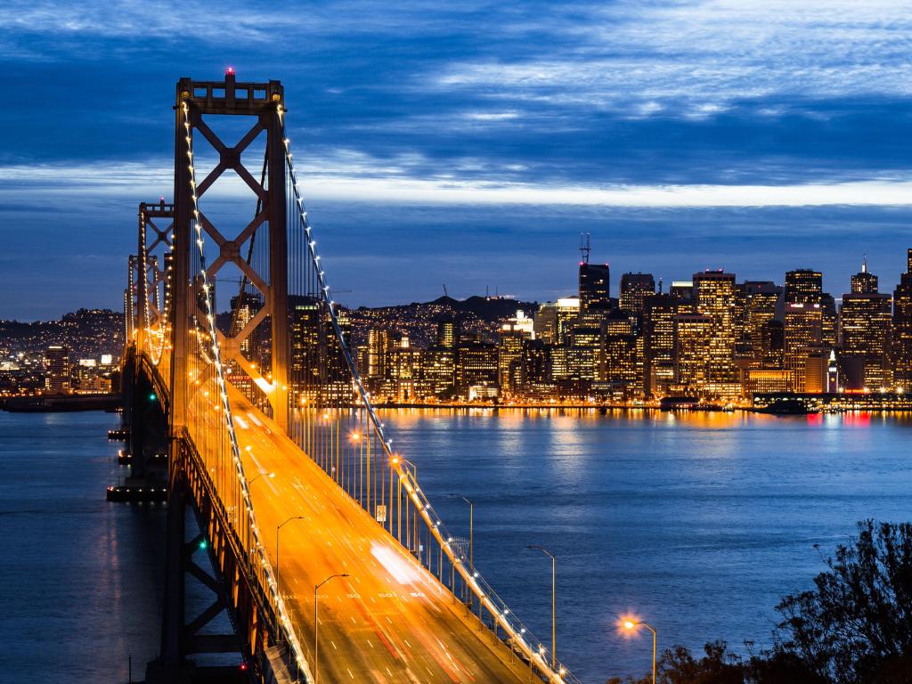 Golden Gate Bridge, San Francisco at night with the bridge lit up in yellow and the city in the background.