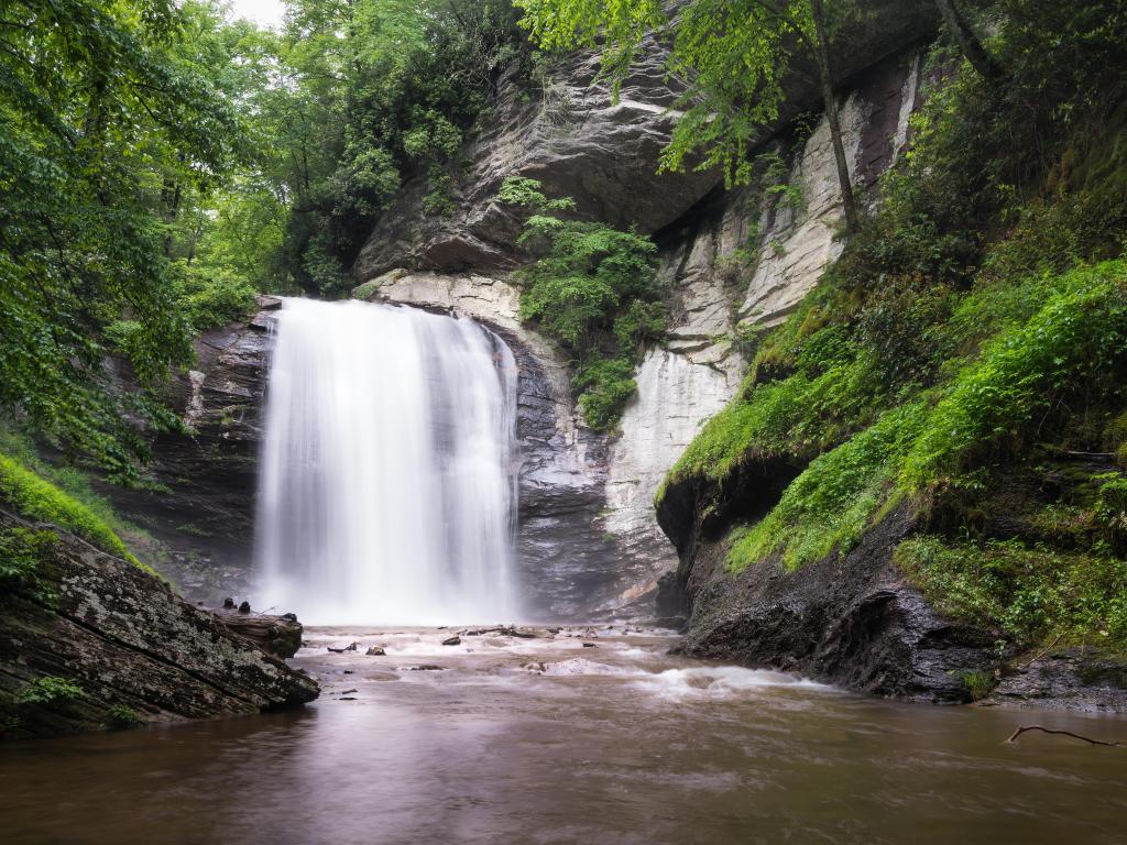 Pisgah National Forest, North Carolina, USA taken at Looking Glass Falls in Brevard with green moss on the rocks and trees in the background.