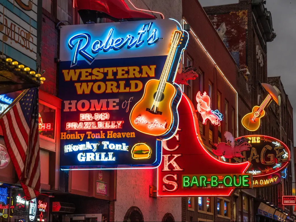 Neon signs for music venues in Nashville, lit up brightly along the street at night